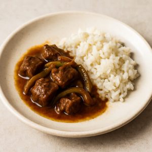 Geschmortes Rindfleisch mit Paprika und Reis auf Teller serviert